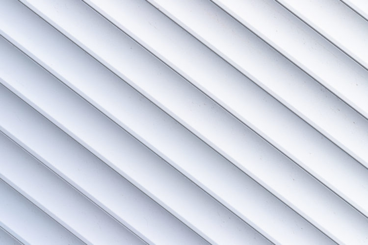 Roller shutter texture. Background with metal stripes in white. Iron roller shutters of white color. Abstract background for wallpaper in the form of straight lines.